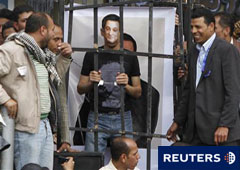Manifestantes se ríen mientras otros se pone una máscara con la imagen del derrocado Mubarak durante un simulacro de juicio en la Plaza Tahrir, el 8 de abril de 2011.