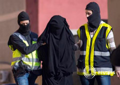 Policías enmascarados llevan a una mujer detenida en una operación antiyihadista en Melilla, el 16 de diciembre de 2014