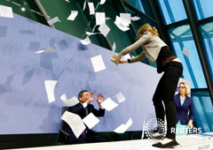 Una manifestante salta sobre la mesa de Draghi durante la rueda de prensa del miércoles 15 de abril de 2015 en Fráncfort