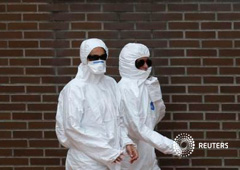 Dos trabajadores a las puertas de la vivienda de la enferma de ébola en Alcorcón (Madrid) el 8 de octubre de 2014
