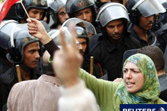 Tercer día de disturbios en Egipto; ElBaradei va a volver Una mujer con la bandera egipcia ante varios agentes antidisturbios en una manifestación en El Cairo el 26 de enero