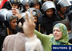 Una mujer con la bandera egipcia ante varios agentes antidisturbios en una manifestación en El Cairo el 26 de enero