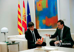 Puigdemont (izq) y Rajoy miran una copia de la segunda parte de 