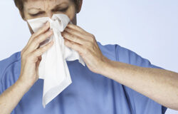 Standard & Poor’s estornuda, y la bolsa coge fiebre Un hombre estornudando mientras se pone un pañuelo en la nariz.