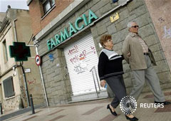 Una pareja pasa junto a una farmacia cerrada en Masnou el 25 de octubre de 2012