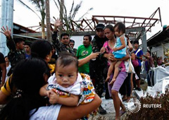 Unos soldados ayudan a unos residentes a salir de Tacloban, una de las zonas más afectadas por el tifón, el 11 de noviembre de 2013