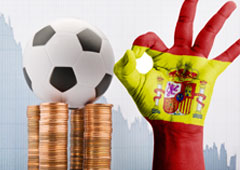 Balón de futbol sobre monedas y con una mano pintada como la bandera española