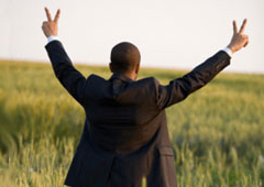 Un hombre de traje en el campo levantando los brazos en señal de victoria.