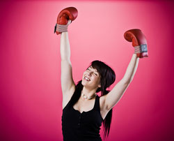 Una chica con los puños en alto con dos guantes de boxeo.