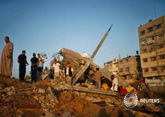 Un grupo de palestinos junto a los escombros de una vivienda que según la policía fue destruida en un ataque aéreo israelí en Gaza el 9 de julio de 2014