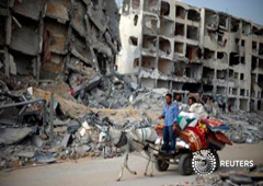 Palestinos pasan frente un barrio destruido en Beit Lahiya, en el norte de la franja de Gaza, el 5 de agosto de 2014