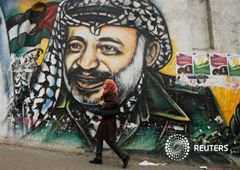 Un estudiante palestino pasea junto a un mural que muestra a Arafat, en Gaza, el 7 de noviembre de 2013