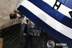 Grecia busca un evasivo acuerdo de rescate y enfada a Europa Un manifestante ondea una bandera griega frente a la policía antidisturbiose junto al Parlamento en Atenas, el 7 de febrero de 2012