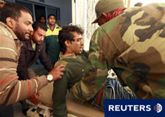 Un combatiente rebelde ayuda a un colega herido trasladado al hospital de Ajdabiya, el 7 de abirl de 2011.