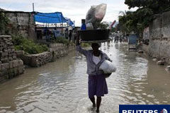 El cólera llega a Puerto Príncipe y se teme una rápida expansión Una mujer haitina lleva pertenencias en una calle inundada en el barrio de Cite-Soleil, en Puerto Príncipe, el 6 de noviembre de 2010