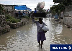Una mujer haitina lleva pertenencias en una calle inundada en el barrio de Cite-Soleil, en Puerto Príncipe, el 6 de noviembre de 2010