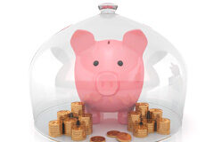 Los fondos con objetivo concreto de rentabilidad incluirán advertencias de que ni el capital ni la rentabilidad están garantizados Una hucha rosa en forma de cerdito, montones de monedas protegidas por un recipiente de cristal