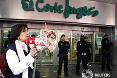 La huelga paraliza la industria, con una calma tensa en la calle Una mujer miembro de un piquete grita consignas junto a unos policías que protegen la entrada de una tienda de El Corte Inglés en Valencia durante la huelga general en España