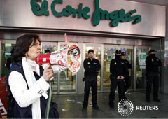 Una mujer miembro de un piquete grita consignas junto a unos policías que protegen la entrada de una tienda de El Corte Inglés en Valencia durante la huelga general en España