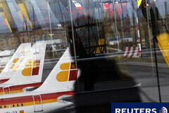 Personal de Iberia amenaza con paros por la filial de bajo coste unos aviones de Iberia reflejados en una ventana al pasar una persona durante la huelga de pilotos del 18 de diciembre