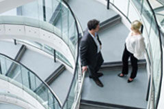 Eficiencia, gobierno corporativo y movilidad internacional, principales retos de los abogados de empresas en España Dos personas conversando en la escalera de una empresa