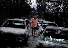 Un hombre camina entre coches calcinados tras un fuego en el pueblo de Mati, cerca de Atenas, Grecia, 24 de julio de 2018 Un hombre camina entre coches calcinados tras un fuego en el pueblo de Mati, cerca de Atenas, Grecia, 24 de julio de 2018