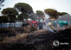 Un hombre ayuda con su tractor a apagar el incendio cerca de Doñana, el 25 de junio de 2017