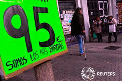 La inflación española reduce su caída en cuatro décimas en mayo Gente pasa por detrás de un cartel publicitario en Sevilla el 12 de diciembre de 2014