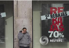 Un hombre habla por su móvil delante de un escaparate de una tienda que anuncia unas segundas rebajas en la Puerta del Sol, en Madrid, el 14 de enero de 2012