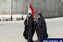 Miles de iraquíes protestan en el «Día de la ira» Dos mujeres con banderas iraquíes piden mejores servicios en el centro de Bagdad el 25 de febrero de 2011.