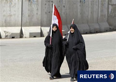 Dos mujeres con banderas iraquíes piden mejores servicios en el centro de Bagdad el 25 de febrero de 2011.