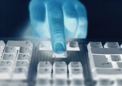 Una mano azul tocando las teclas de un ordenador.