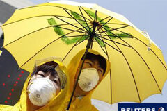 Japón eleva la severidad de la crisis nuclear al máximo nivel Gente con máscaras y chubasqueros y paraguas amarillos participan en una manifestación antinuclear para exigir al gobierno que difunda con rapidez información sobre la "lluvia radiactiva" y los riesgos de la radiactividad, en Seúl, el 12 de abril de 2011