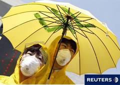 Gente con máscaras y chubasqueros y paraguas amarillos participan en una manifestación antinuclear para exigir al gobierno que difunda con rapidez información sobre la 
