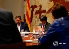 El presidente catalán, Carles Puigdemont (D), y el vicepresidente Oriol Junqueras, leen documentos durante una reunión de su Ejecutivo, en Barcelona, el 24 de octubre de 2017