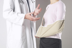 Una mujer con el brazo lesionado hablando con un medico.