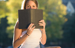 Cuando la distribución editorial es en exclusiva Una chica tapándose la mitad de la cara con un libro.