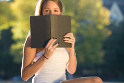 Una chica tapándose la mitad de la cara con un libro.
