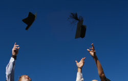 La Universidad y los licenciados que saca a la calle Tres licenciados con los diplomas en la mano, lanzan los bonetes con flecos al aire