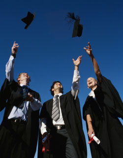 Tres licenciados con los diplomas en la mano, lanzan los bonetes con flecos al aire