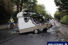 Las ciudades británicas sufren más saqueos; Londres, en calma Un ciclista pasa junto a una caravana incendiada en Toxteth (Liverpool) el 10 de agosto de 2011.