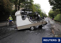 Un ciclista pasa junto a una caravana incendiada en Toxteth (Liverpool) el 10 de agosto de 2011.