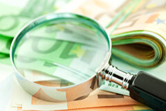 Traslado del domicilio social, ¿también del domicilio fiscal? Una lupa aumentando billetes de euro