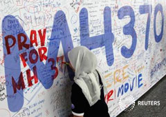 Una mujer escribe un mensaje en una pancarta de apoyo a los pasajeros del vuelo MH370 de Malaysia Airlines en Kuala Lumpur el 14 de marzo de 2014
