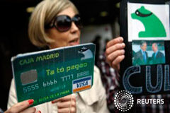 El juicio por las ‘tarjetas Black’ se retrasa hasta el próximo 26 de septiembre, tres días más tarde de lo previsto Una manifestante con un cartel que simula una tarjeta falsa de Caja Madrid