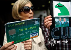 Una manifestante con un cartel que simula una tarjeta falsa de Caja Madrid
