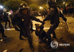 una manifestante grita mientras es arrastrada por la policía antidisturbios en Madrid