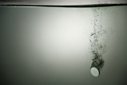 Una pastilla cayendo en un vaso de agua.