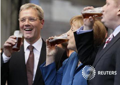 La canciller Angela Merkel bebe cerveza negra tras un mitin de campaña electoral con Norbert Roettgen (I), principal candidato del partido democratacristiano CDU en las elecciones del estado de Renania del Norte-Westfalia, en Düesseldorf