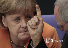 la canciller alemana Angela Merkel habla con el ministro de Finanzas, Wolfgang Schaeuble, durante una sesión del parlamento alemán para aprobar el rescate a los bancos españoles, en Berlín